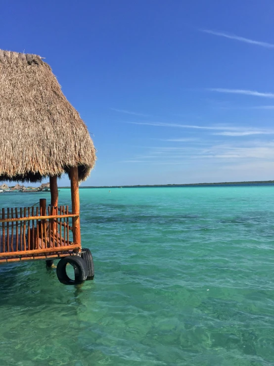 the dock to the water has a straw hut with an attached platform