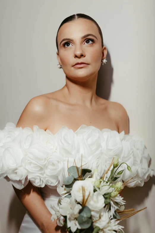 a young woman wearing a white gown holding a bouquet of flowers