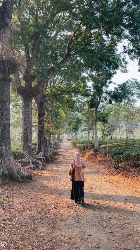 two women standing on a dirt road between trees