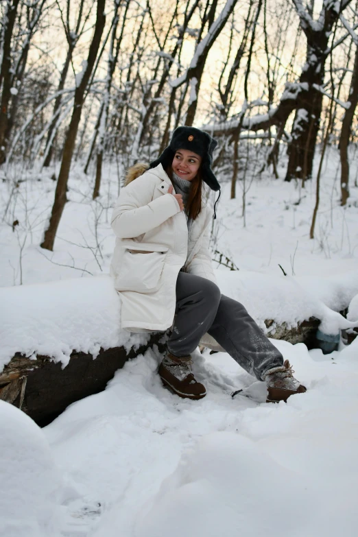 a woman is posing with her snowboard in the woods
