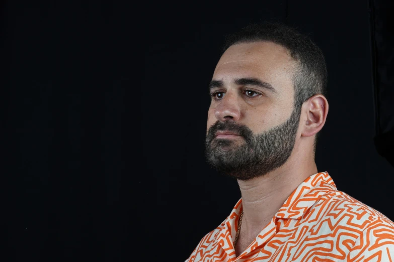 a bearded man with a white and orange shirt