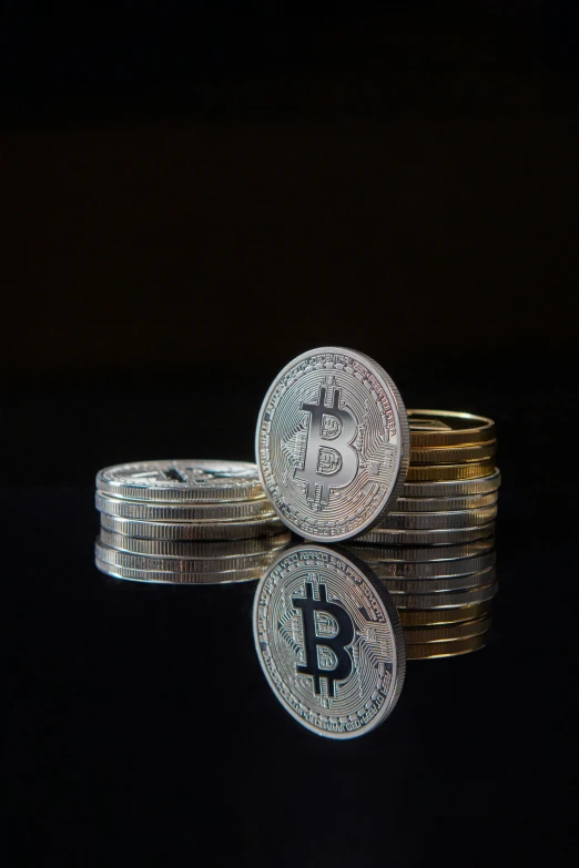 stack of silver and gold bitcoins against black background