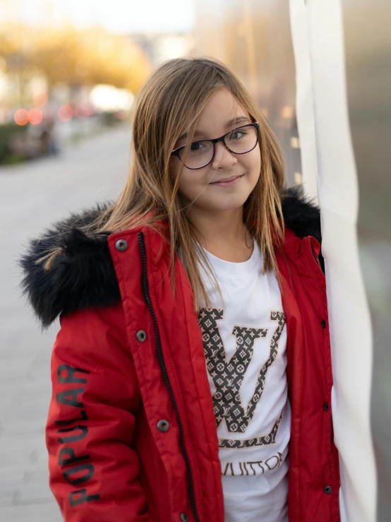 a girl wearing glasses standing in front of a pole