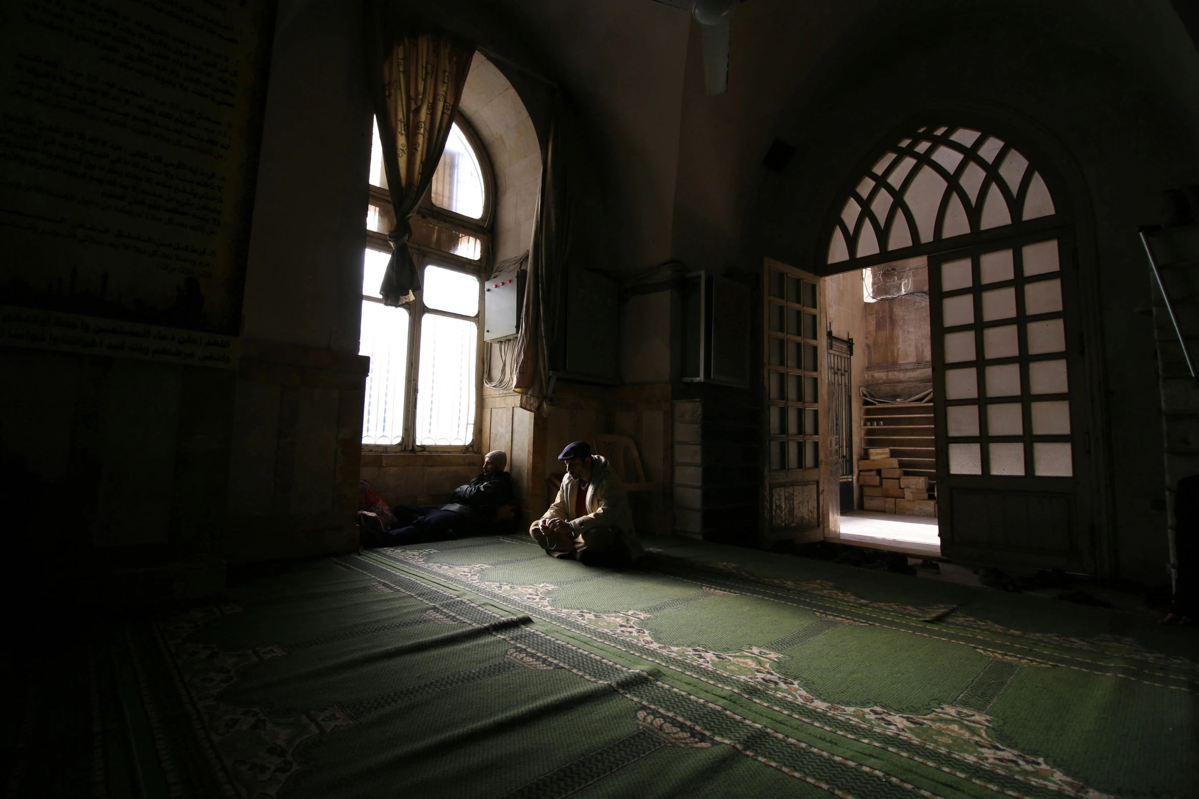 a person kneeling down by a door with large windows