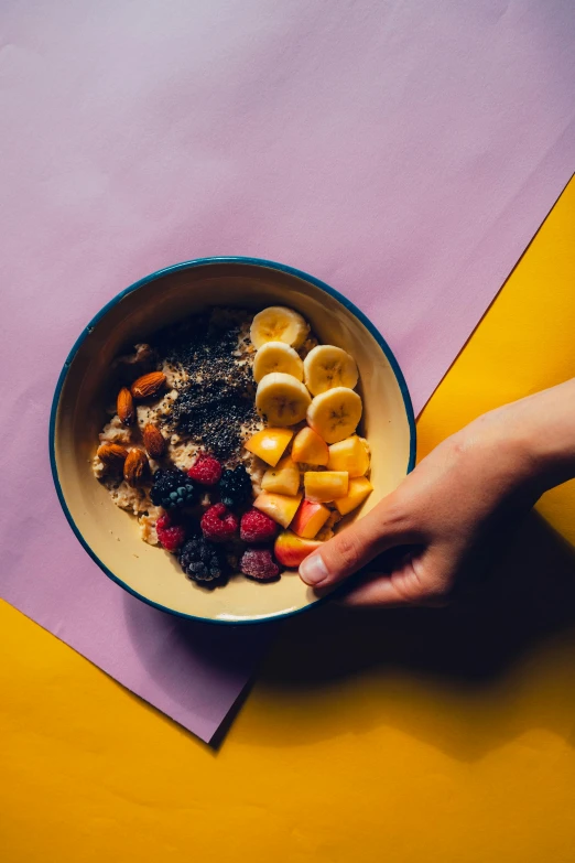 a hand reaching for fruit in a bowl