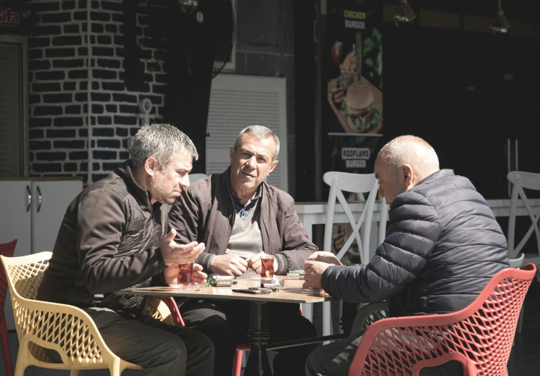 a couple of men sitting around a table with chairs