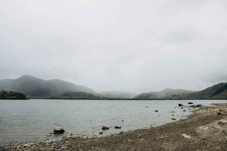 water with rocks along a beach and a cloudy sky