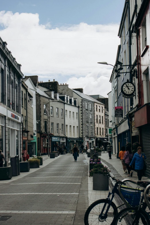 people walking down a street with buildings and bicycles