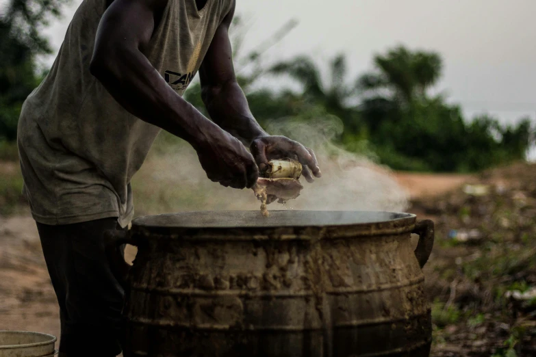 a man pouring honey into a bucket with a wooden handle