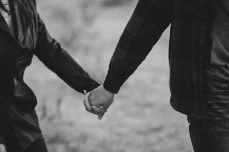 two people holding hands while walking