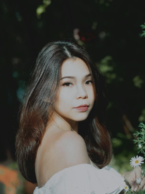 young woman posing for a portrait, in a white top with a flower