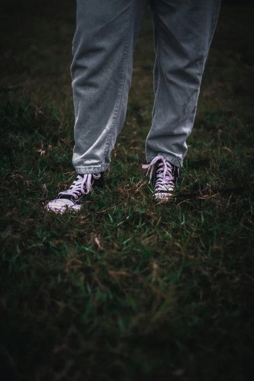 a person wearing sneakers stands on the grass