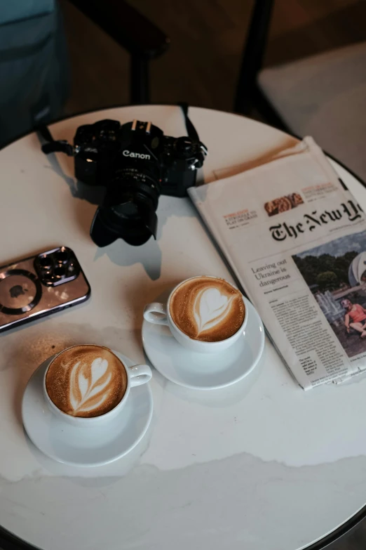 two cups with coffee sitting next to each other on a table