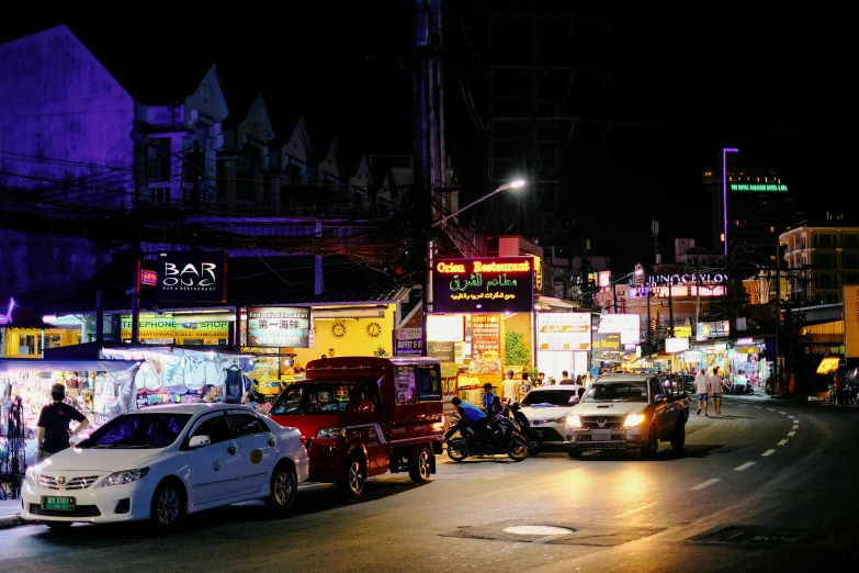 several vehicles are parked along the street in front of shops