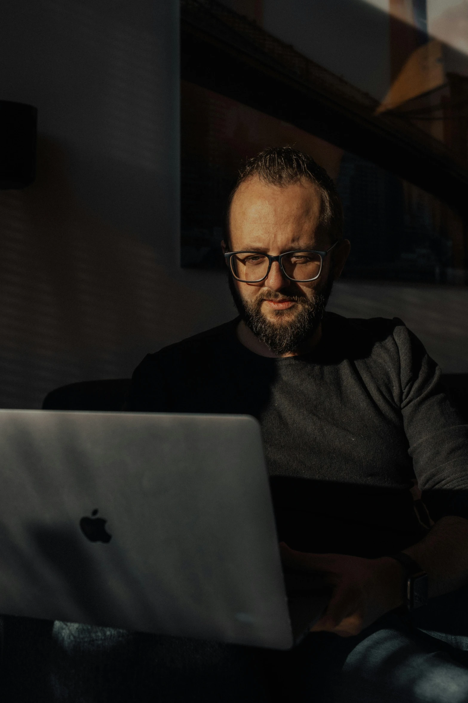 a man with glasses on, looking at a laptop computer