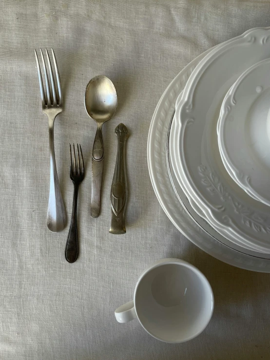 a table with three plates, four forks and four spoons