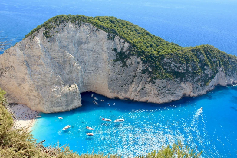 boats floating in the blue waters on a sandy beach