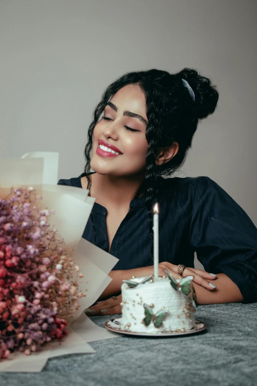 woman with candles smiling next to her white cake