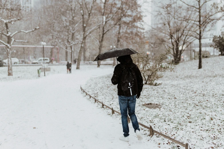 a person walks on the side walk with a umbrella