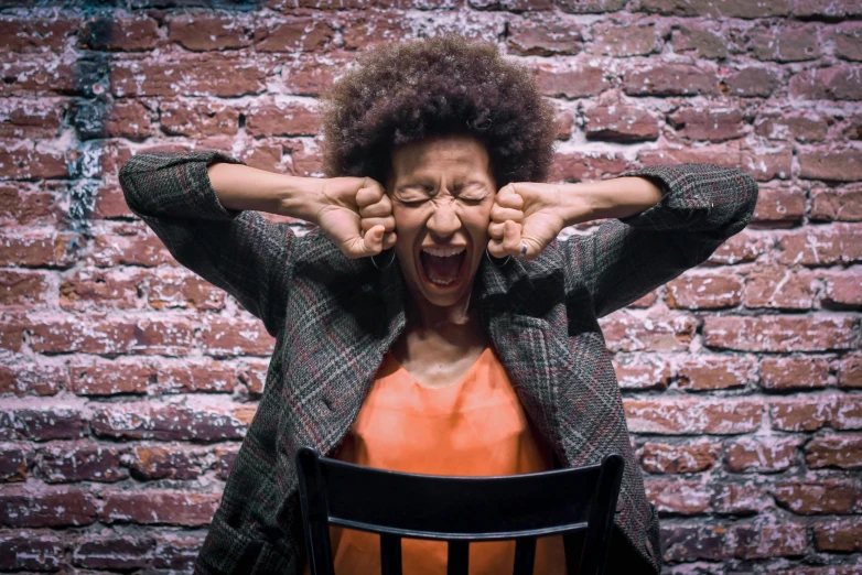 a woman with an open mouth in front of a red brick wall