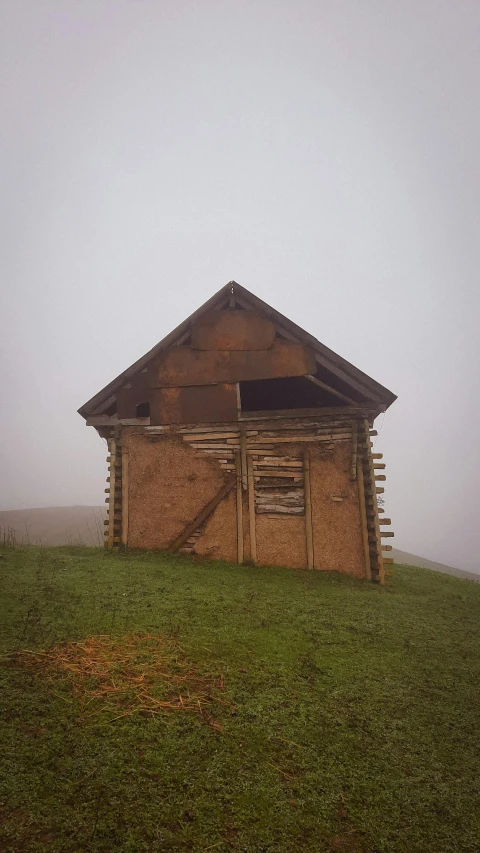 an old wooden cabin on top of a green field