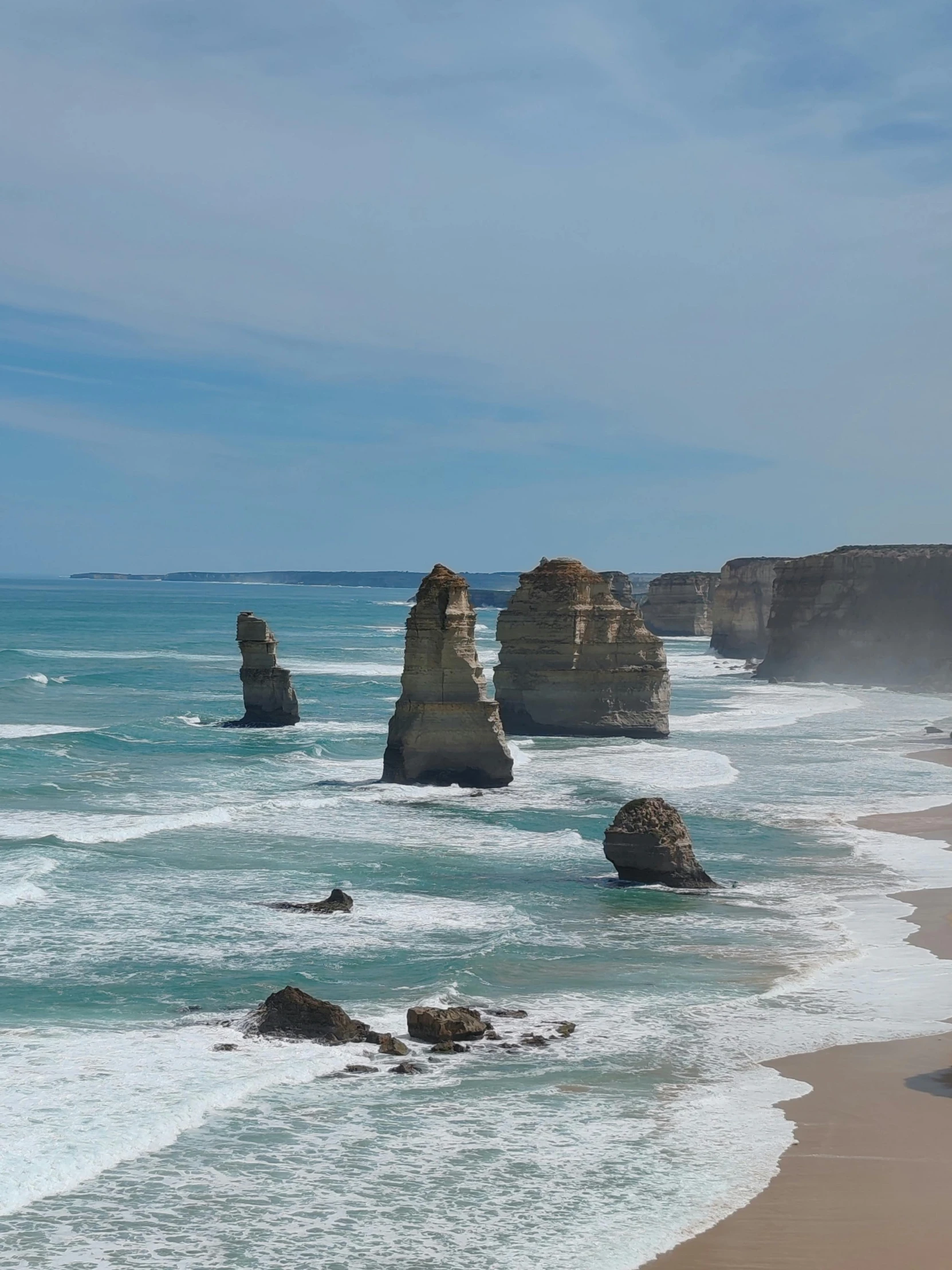 the ocean has many large rocks along with the shore