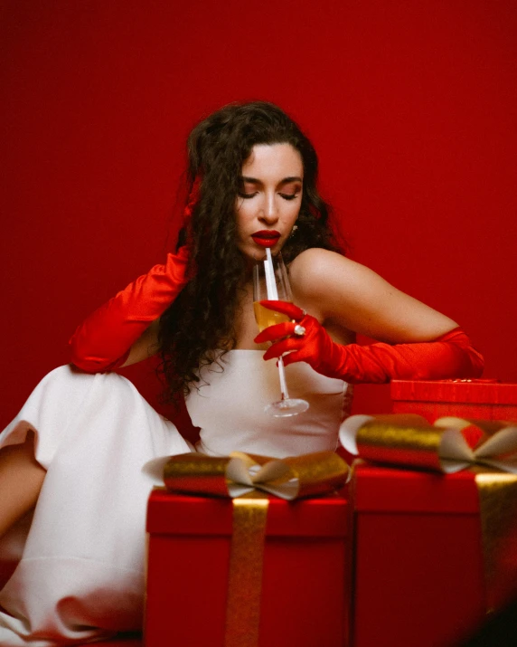 a woman in a red dress with red gloves sitting next to a box