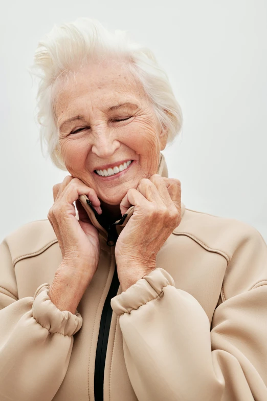 an old woman with white hair is smiling and talking on a phone