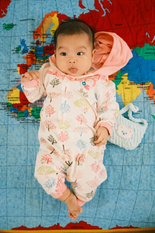 a baby girl laying on a map in her pajamas