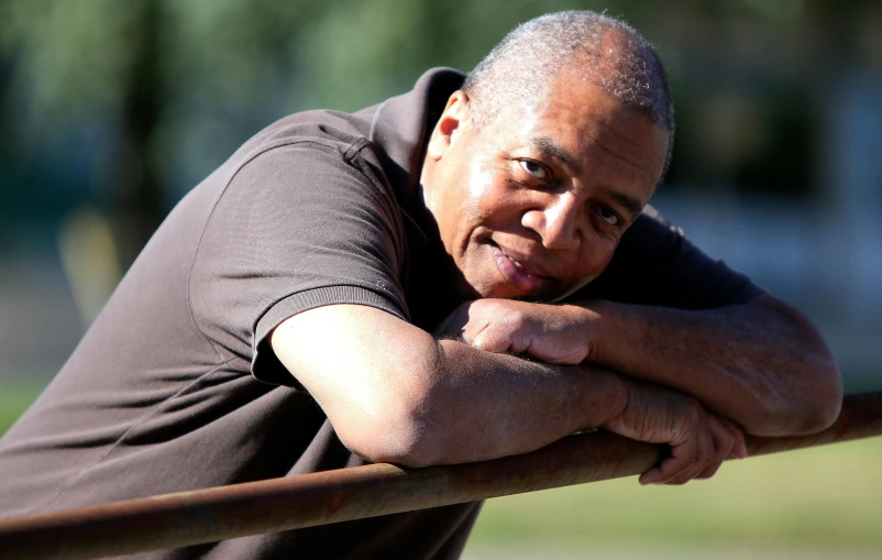 an older man is leaning on a fence and looking off into the distance