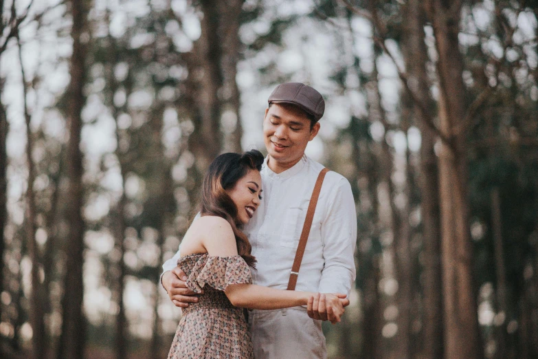 the young man is hugging his girlfriend while posing in the woods