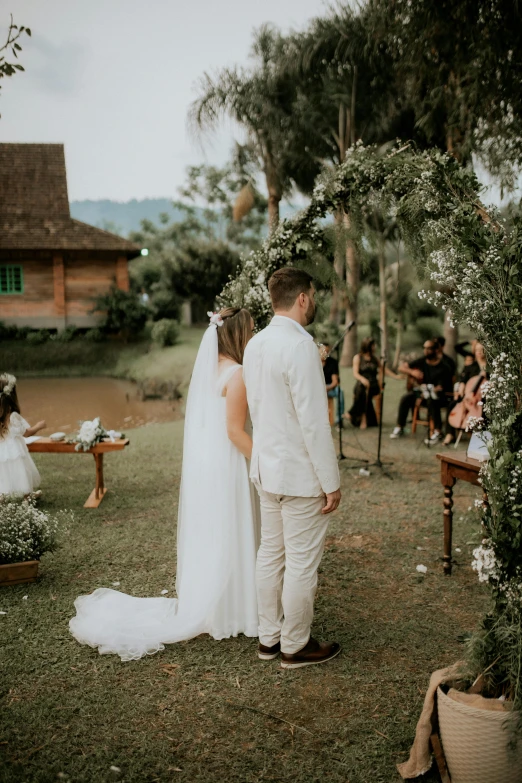 a couple at their outdoor wedding ceremony standing under a floral archway