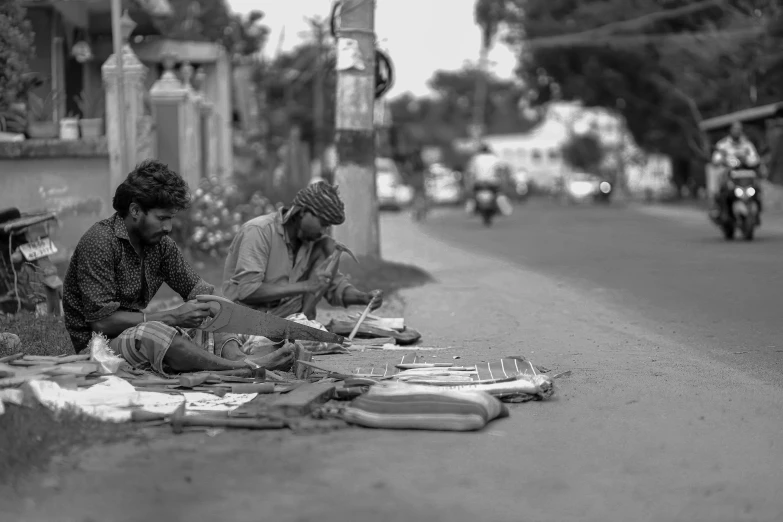 two people are sitting on the side walk, and one has plates with food on it