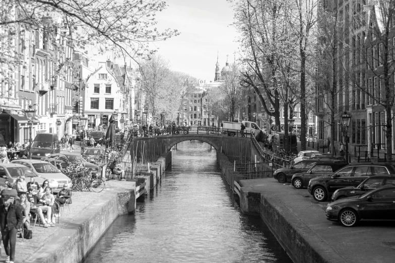 cars and motorcycles on street lined with canal