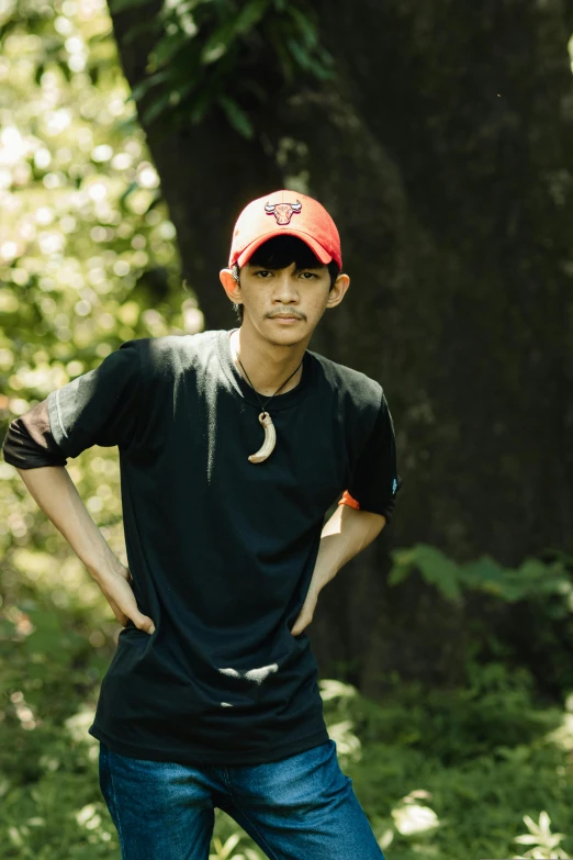 a young man posing for a picture in front of a tree