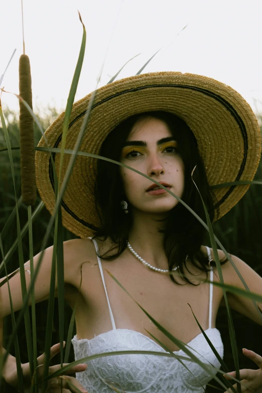 the woman in the hat is standing amongst the tall grass