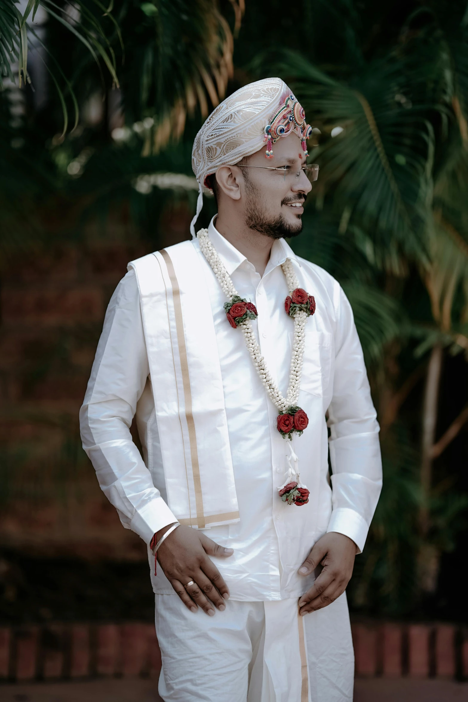 an ethnic man wearing white clothes with decorations on his head