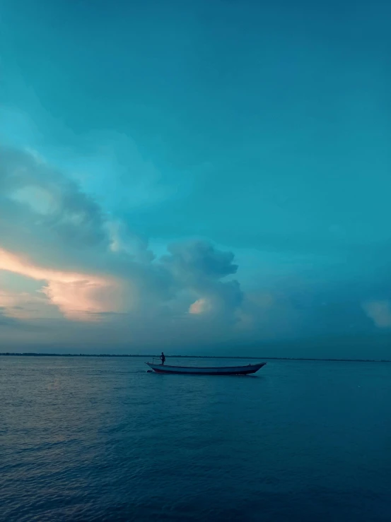 a fishing boat out on the water during a dark blue sky