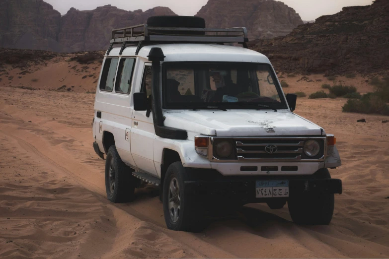 an suv driving on sand, in the desert