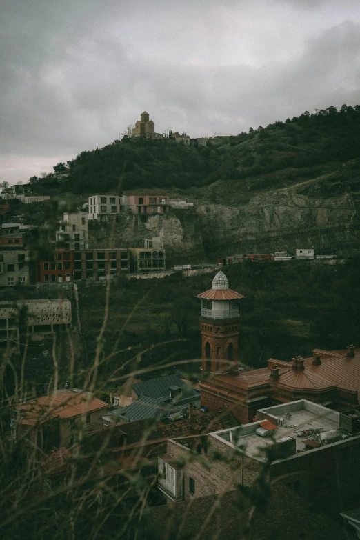 there is a tower near some buildings on the hill