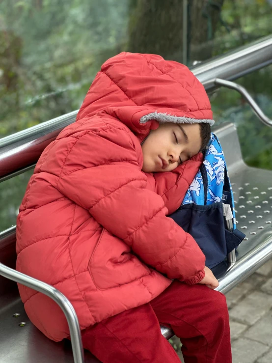 a small boy sleeps on a bench as the rain passes