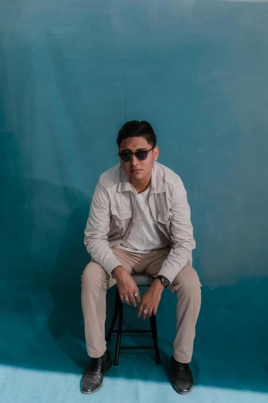 a man sitting on top of a stool in a studio