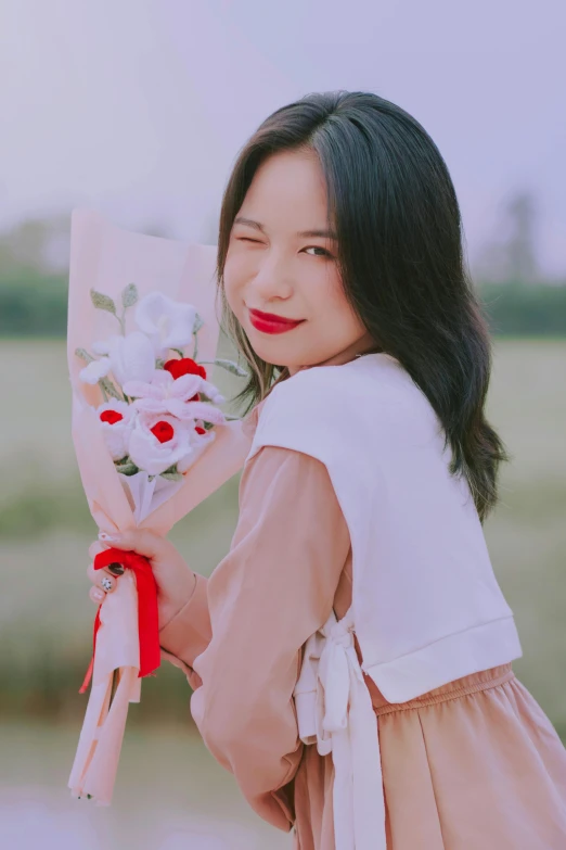 a woman holding a bouquet of flowers by a field