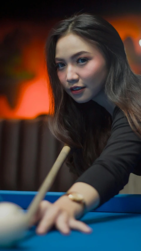 a woman is playing pool on a blue table