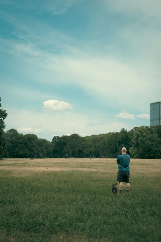 the man is flying a kite while his dog watches