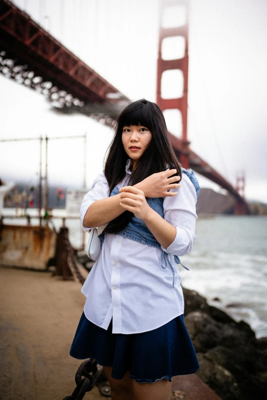 a woman is posing by the golden gate bridge in her skirt