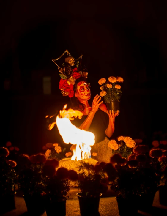 a man is holding flowers and sitting around fire