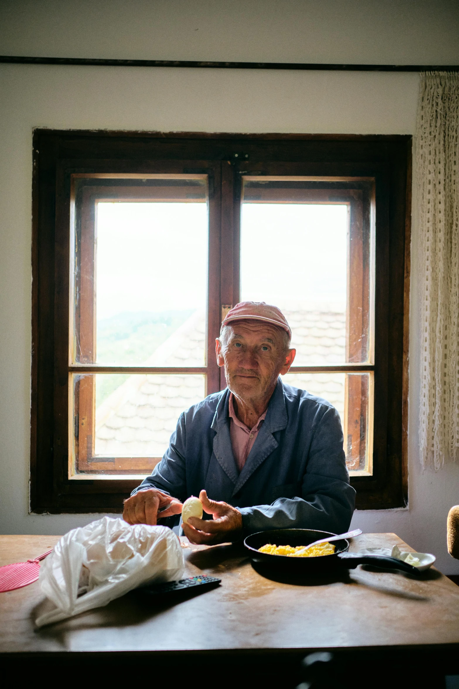 a man sitting in front of a window next to some food