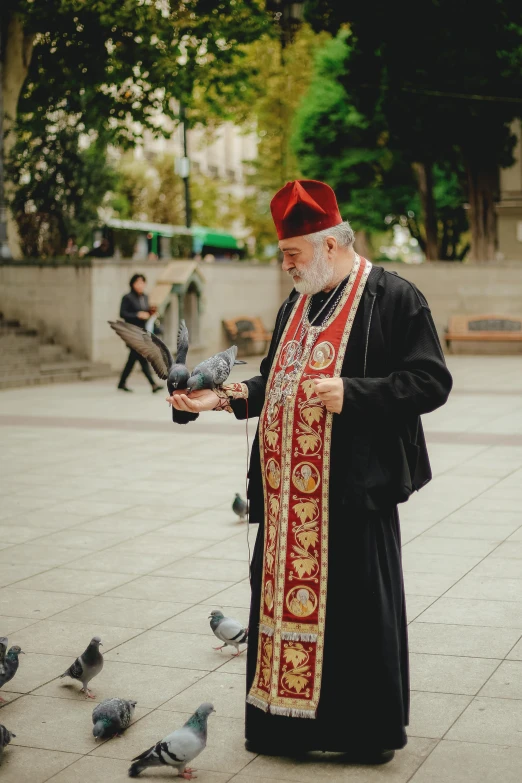 a man standing outside feeding pigeons from his hands