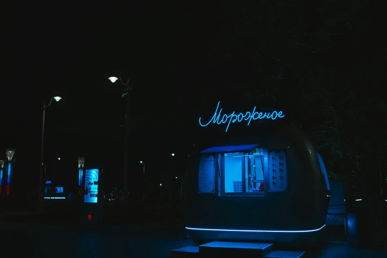 illuminated cell phone booth at night next to trees